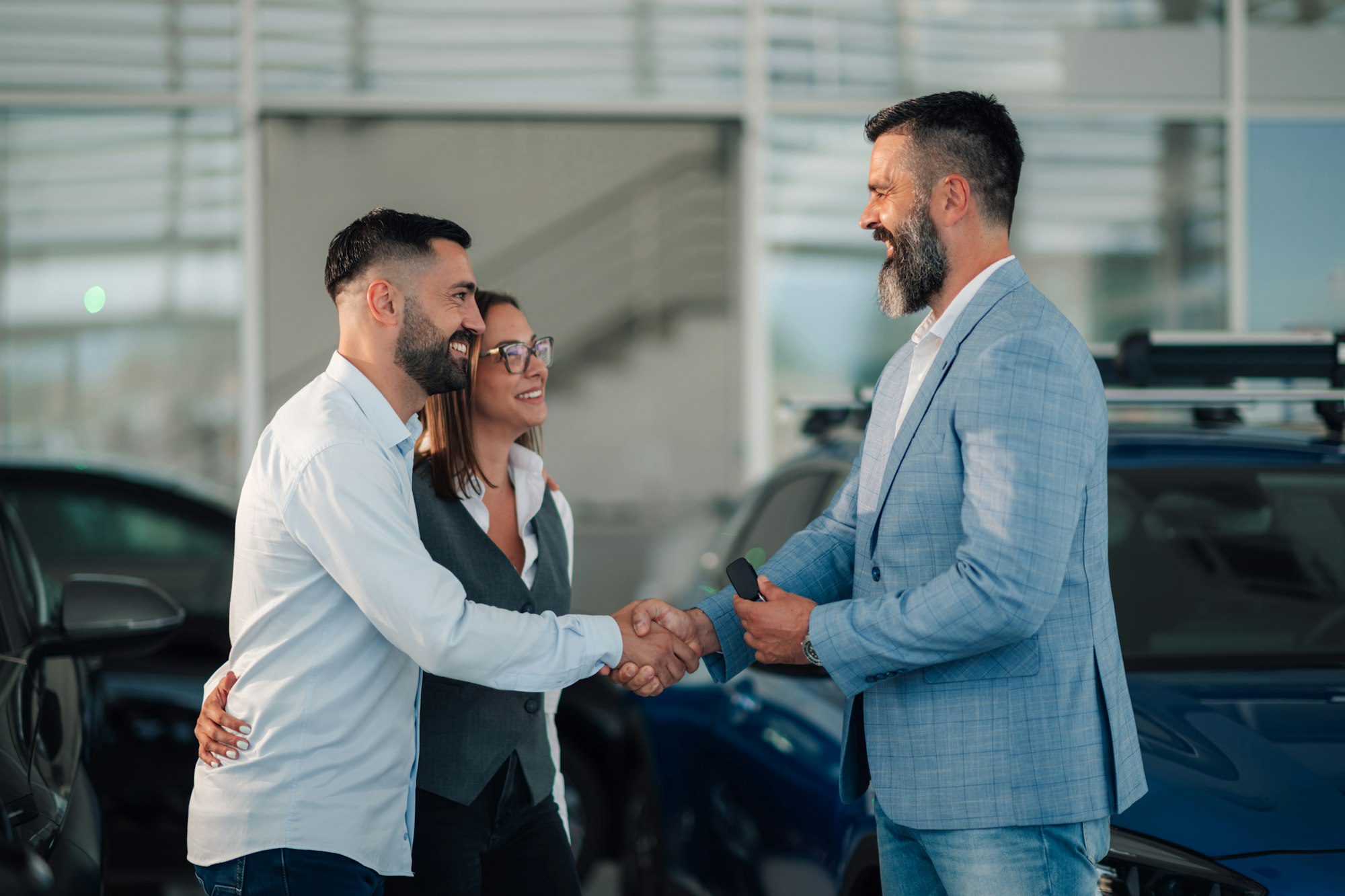 salesman handing over car keys to a couple in a car dealership